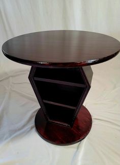 a round wooden table sitting on top of a white sheet