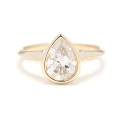 a yellow gold ring with a pear shaped diamond in the center, on a white background