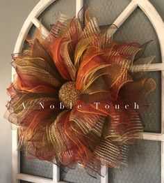 an orange and gold mesh wreath on a door