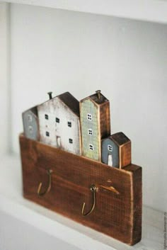 a wooden shelf with some small houses on it's sides and hooks hanging from the side