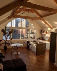 a living room filled with furniture next to a kitchen and dining table in front of a large window