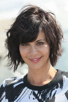 a close up of a person with a smile on her face and hair in the wind