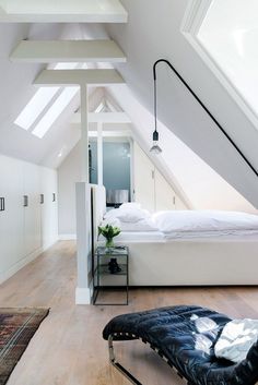 an attic bedroom with white walls and wooden floors