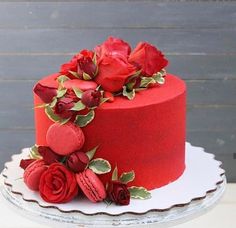 a red cake decorated with roses and leaves