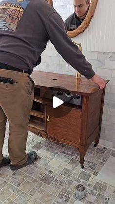 a man standing in front of a wooden desk with a mirror on top of it