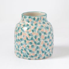 a ceramic vase with green and orange dots on it