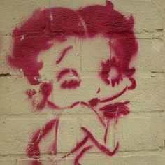 graffiti on the side of a building with a woman's face painted in pink