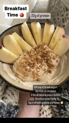 a bowl filled with oatmeal and apples on top of a table next to a person's hand