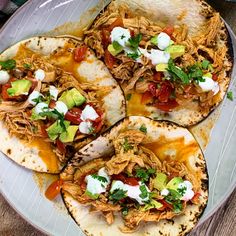 four tacos on a plate with sour cream and avocado garnishes