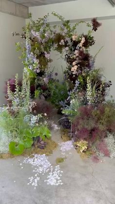 an arrangement of flowers and plants on display in a room with concrete flooring,