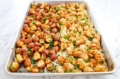 a pan filled with stuffing and vegetables on top of a marble countertop next to a knife