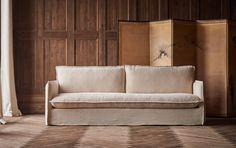 a white couch sitting in front of a wooden wall