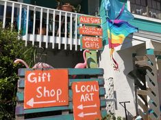 colorful wooden signs on the side of a building advertising gift shops and local art supplies