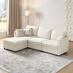 a living room with a sectional couch and rug in front of a large window on the floor