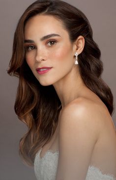 a beautiful woman in a white dress with long hair and diamond earrings on her head