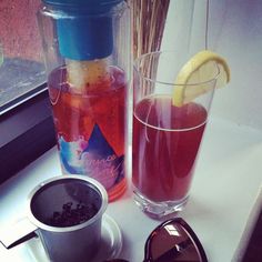 a cup of tea, sunglasses and a bottle of water sit on a window sill