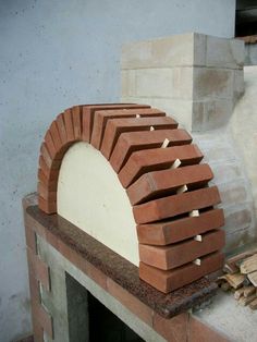 a brick oven sitting on top of a counter next to a pile of wood and bricks