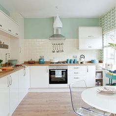 a kitchen filled with white appliances and lots of counter space next to a dining room table