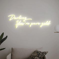 a neon sign that reads, dancing is your own god on the wall next to a couch