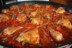 a pan filled with chicken and peppers on top of a stove