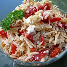 a glass bowl filled with pasta and tomatoes