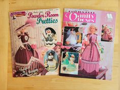 two magazine covers with dolls on them sitting on a table next to each other in front of a wooden surface