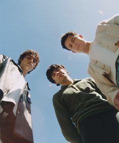 three men standing next to each other looking up at the sky