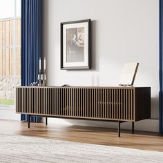 a wooden sideboard in a living room next to a window with blue drapes