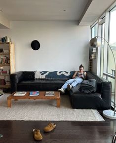 a man sitting on top of a black couch in a living room