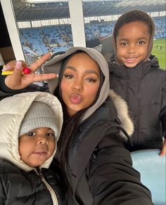 two children posing for a photo in front of a window at a soccer stadium with their fingers up