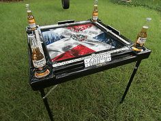 two beer bottles sitting on top of a table in the middle of a grassy field