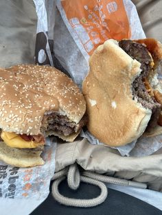 two hamburgers sitting next to each other on top of a bag