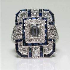 an art deco diamond and blue sapphire ring with diamonds surrounding the center, set in 18k white gold