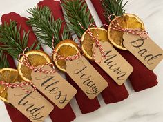 four orange slices tied with twine on top of red napkins next to evergreen branches