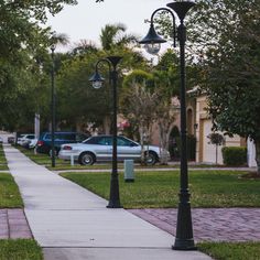 the sidewalk is lined with street lamps and parked cars