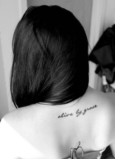 the back of a woman's shoulder with words on it that read, alive by grace