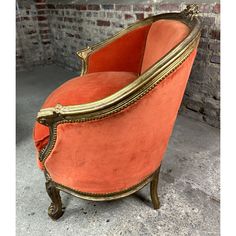 an orange velvet chair with gold trim