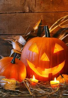 two carved pumpkins sitting next to each other with candles in front of them on the ground