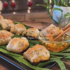 some food that is sitting on top of a leafy green platter with dipping sauce