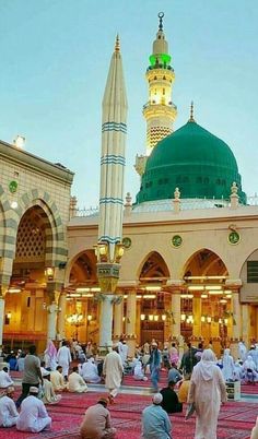 many people are sitting on the ground in front of a building with a green dome