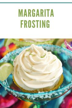 a cupcake with white frosting and lime on top in a blue glass dish