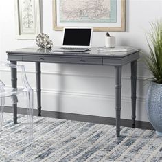 a laptop computer sitting on top of a wooden desk next to a chair and potted plant