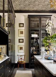 a kitchen with black cabinets and white counter tops, along with pictures on the wall