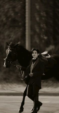 black and white photograph of a woman walking with a horse on the street in front of her