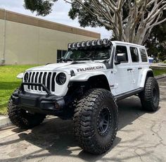 a white jeep parked in front of a tree