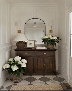 there is a vase with white flowers on the dresser in the room and a mirror above it