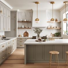 a kitchen with marble counter tops and gold pendant lights hanging from the ceiling over the island