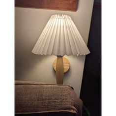 a lamp that is on top of a table next to a bed with a wooden headboard