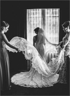 two women in dresses and veils are looking at another woman's wedding dress