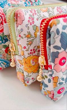 three zippered pouches are lined up on a white surface with flowers all over them